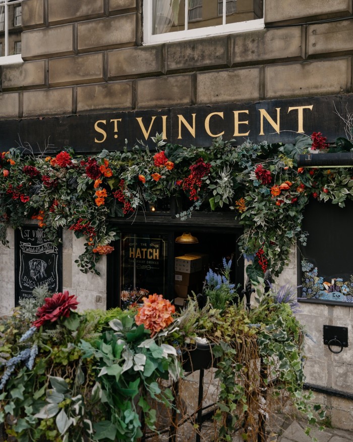 The grey-brick facade of the St Vincent Bar, with flowers in boxes beneath its sign 