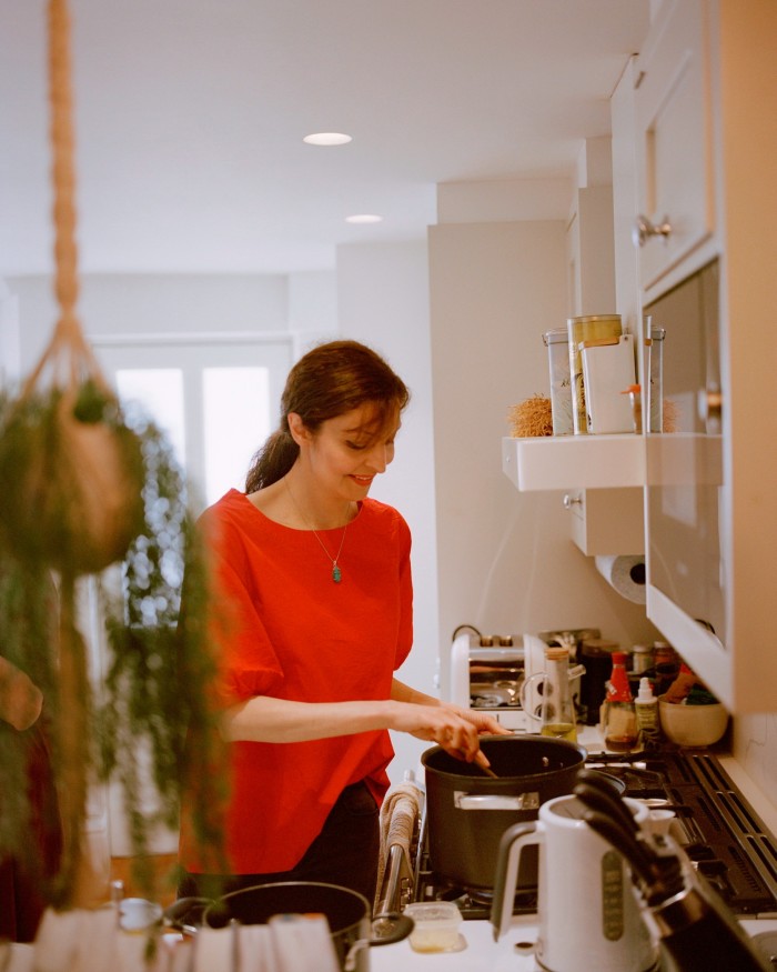 A woman in a red top stands by a stove