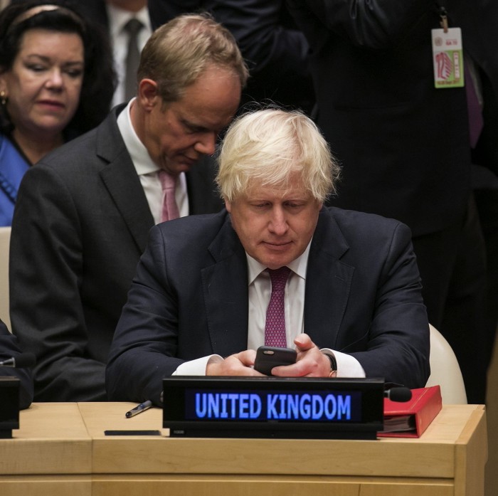 Boris Johnson sits at a meeting behind an illuminated panel that says ‘United Kingdom’