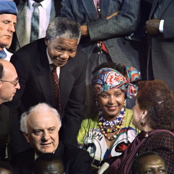 The faces of Nelson Mandela and Winnie Mandela, wearing a colourful headress, seen from above in the midst of a crowd