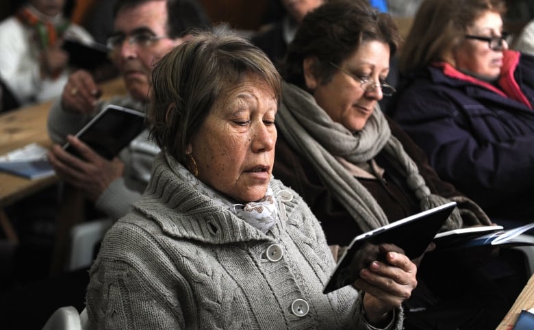 A room of retirees look down at their new tablet computers.