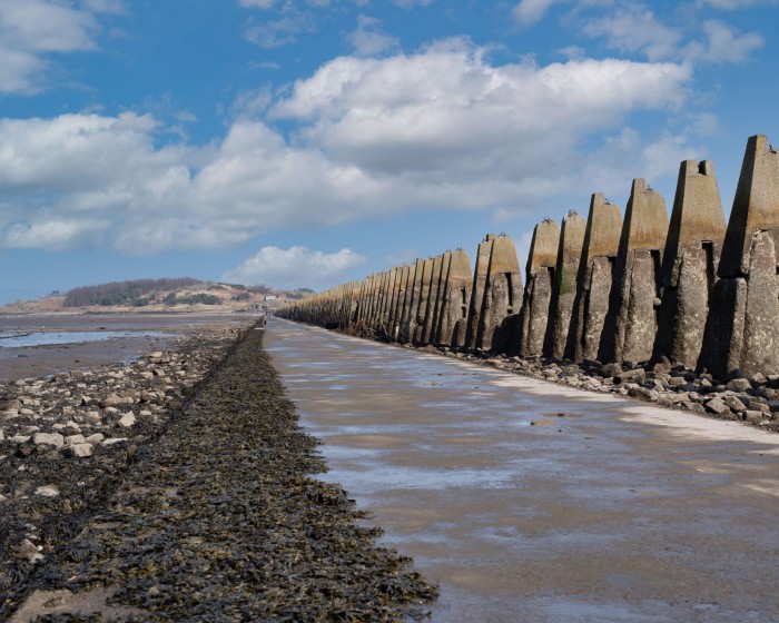 A row of anti-submarine defences leading to Cramond Island in the distance 