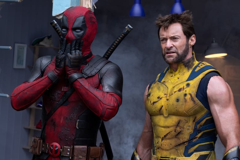 Ryan reynolds dressed as deadpool looking surprised on left, Hugh Jackman dressed as Wolverine on right, staring off-screen.