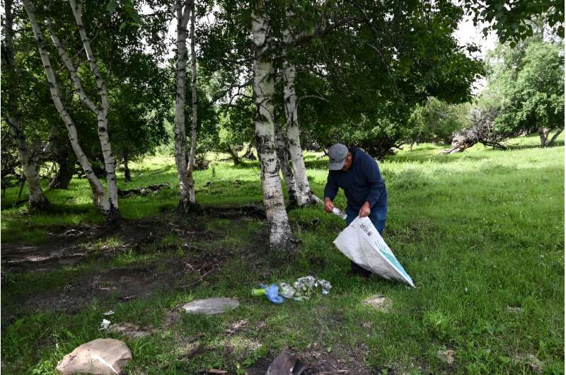 Herder Purev Batmunkh picks through waste strewn across a field in rural Mongolia