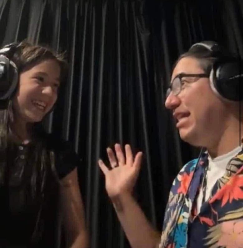 A man and girl wearing headphones smile in a studio