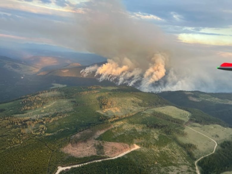 A view of smoke and green hillsides from the air.