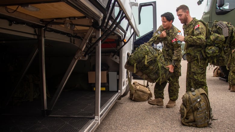 Canadian soldiers load bags into a bus.