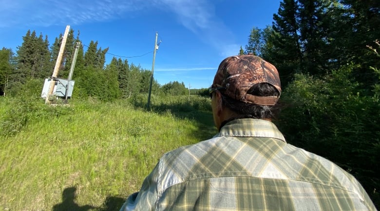 A hydro tower with a guy wearing a hat that says Native Pride standing in front.