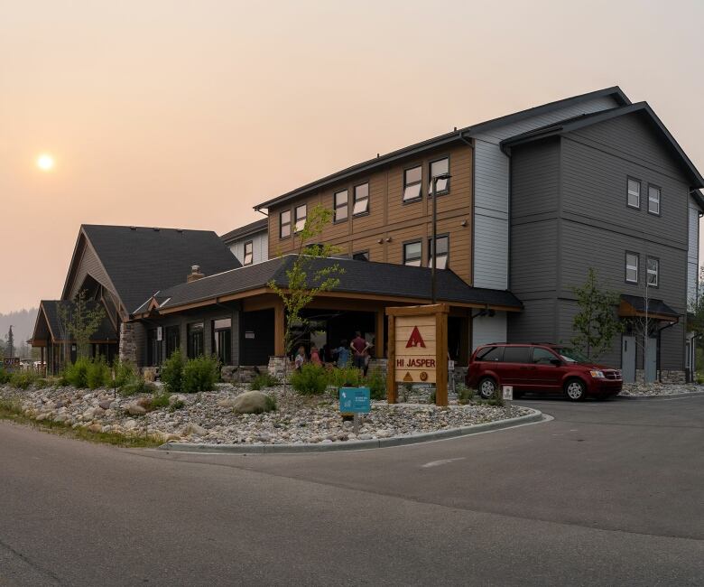 A hotel-style lodge in front of a hazy sunset.