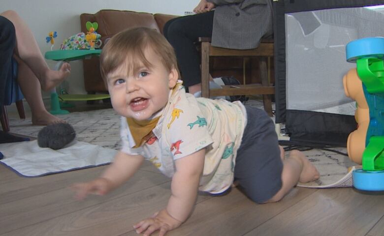 Baby crawls on floor with big smile