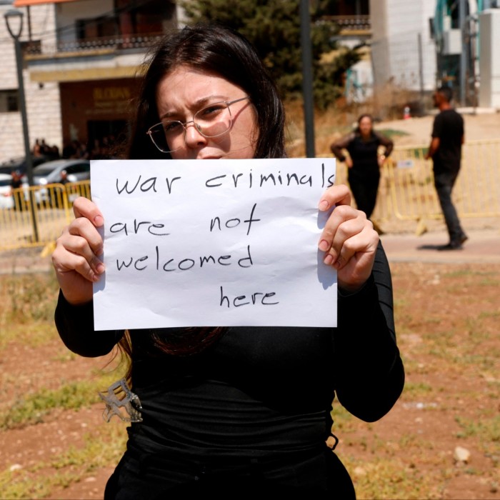 A woman holds a poster as she and others demonstrate against the Israeli Prime Minister during his visit to the Druze village of Majdal Shams