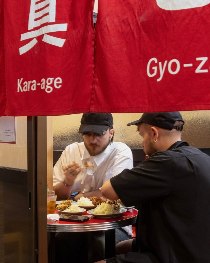  Two men in baseball caps dining at a table in Izakaya Masaka