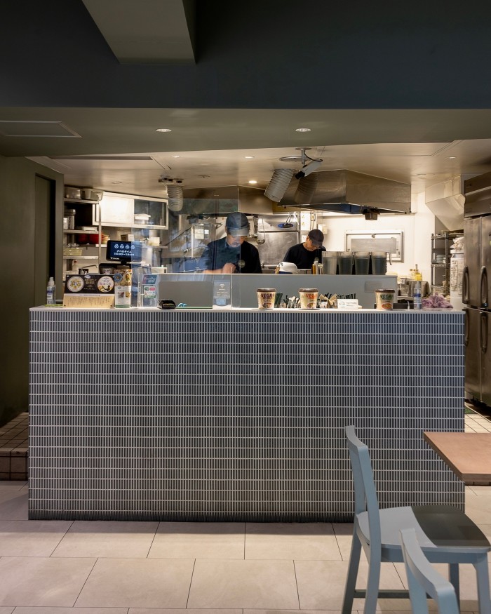 Two men working behind the grey-stone counter of Vegan Bistro Jangara