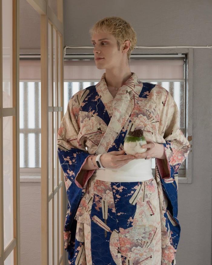 James Brown, the café’s American founder, wearing a blue and white kimono and holding a glass tumbler containing a green and white plant-based pudding