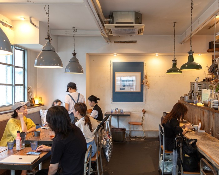 Diners at rustic-style wooden tables beneath pendant lamps at Alaska Zwei