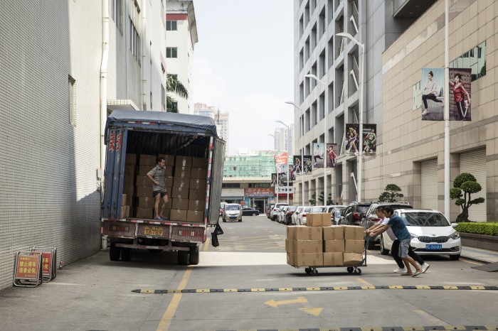 Workers push a cart of boxed shoes towards a truck at the Anta factory in Jinjiang, Fujian