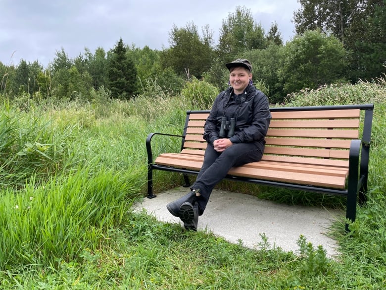 A young person sitting on a pack bench.