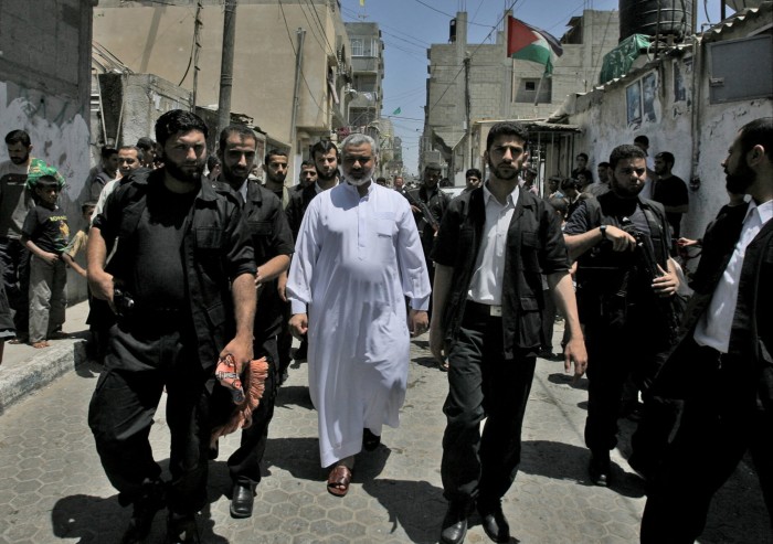 Ismail Haniyeh surrounded by military figures walking through Gaza