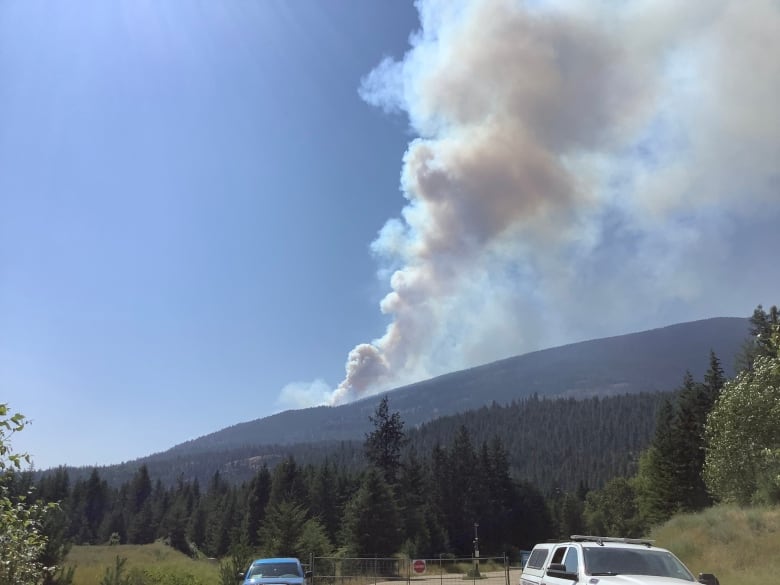 Smoke rises from a hill on a sunny day.