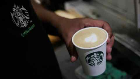 A Starbucks barista holding a cup of coffee