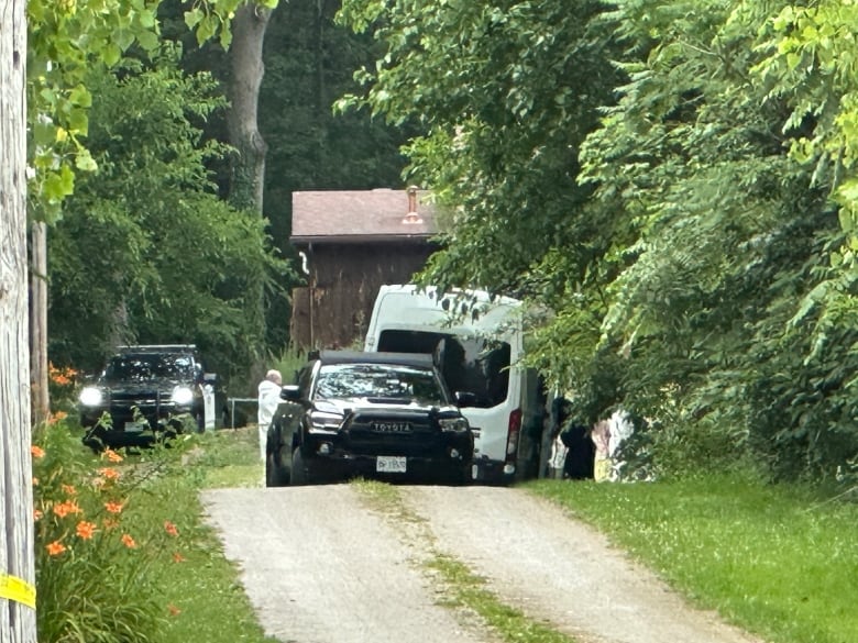 Investigators in white overalls at a rural home.