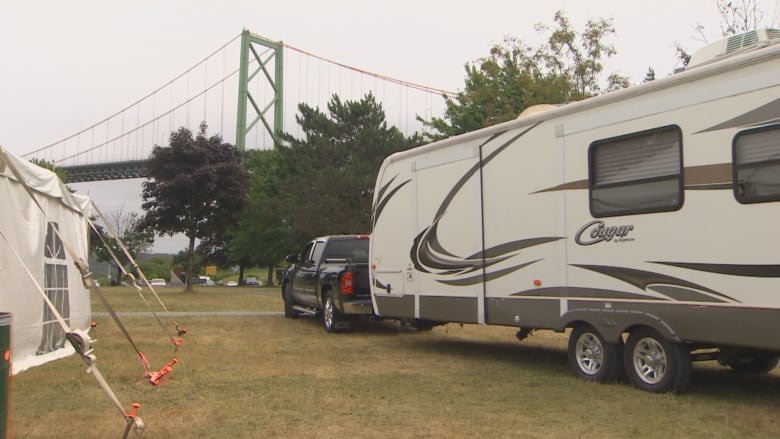 A pickup truck hauls a trailer out of a park.