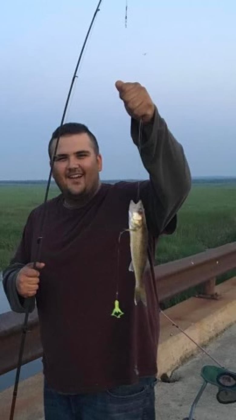 A man holds a fishing rod with a fish on it.