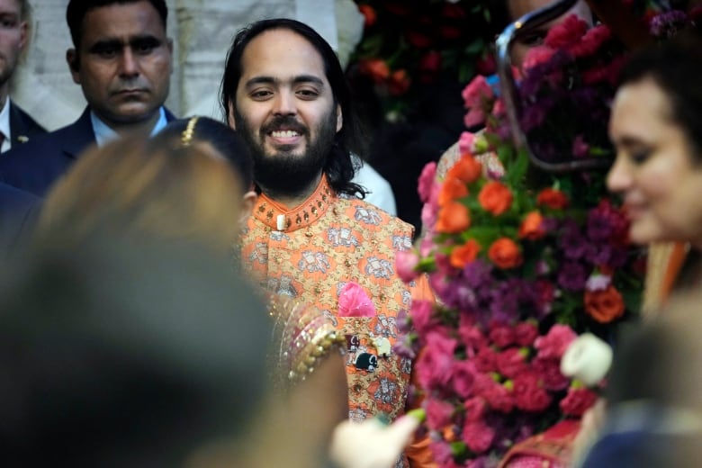 A man, surrounded by people, smiles.