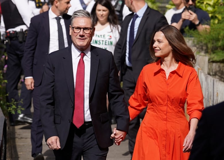 A man and woman walk down a street holding hands.