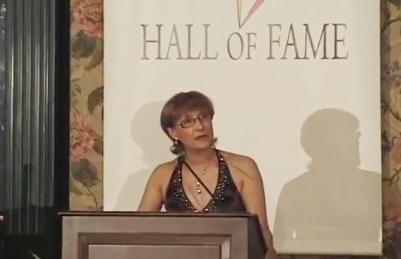 Woman at podium with the words "hall of fame" behind her