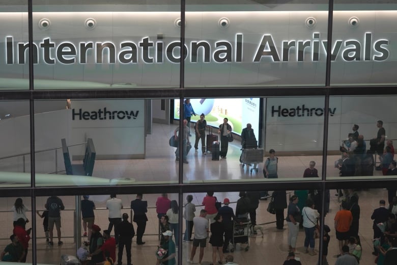 A roomful of passengers at London's Heathrow International Airport is shown.