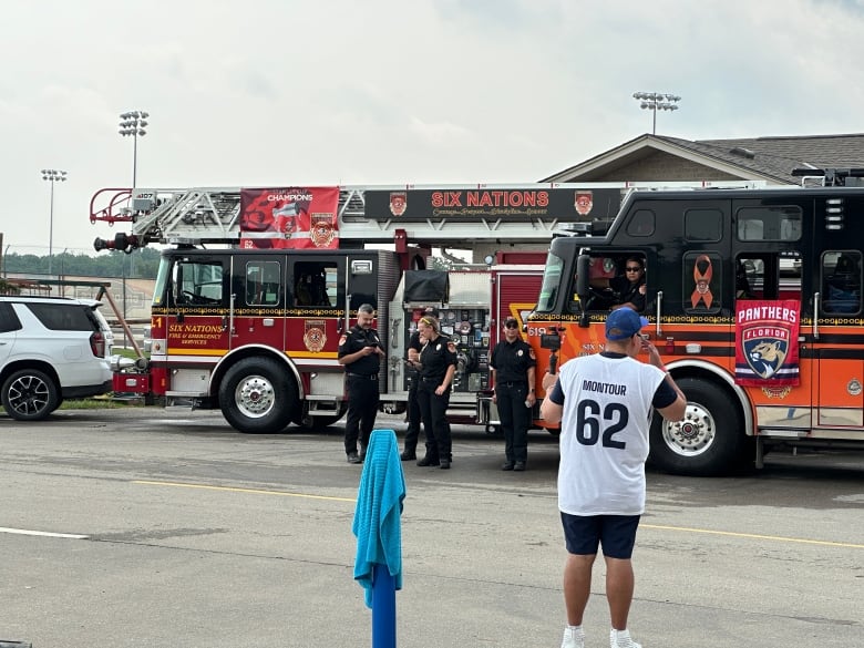 A fire truck from Six Nations is seen behind a person standing with a Montour jersey on. 