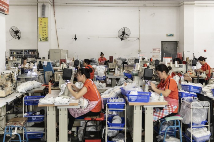 Workers operate sewing machines on the footwear production line at an Anta Sports factory in Jinjiang, Fujian province