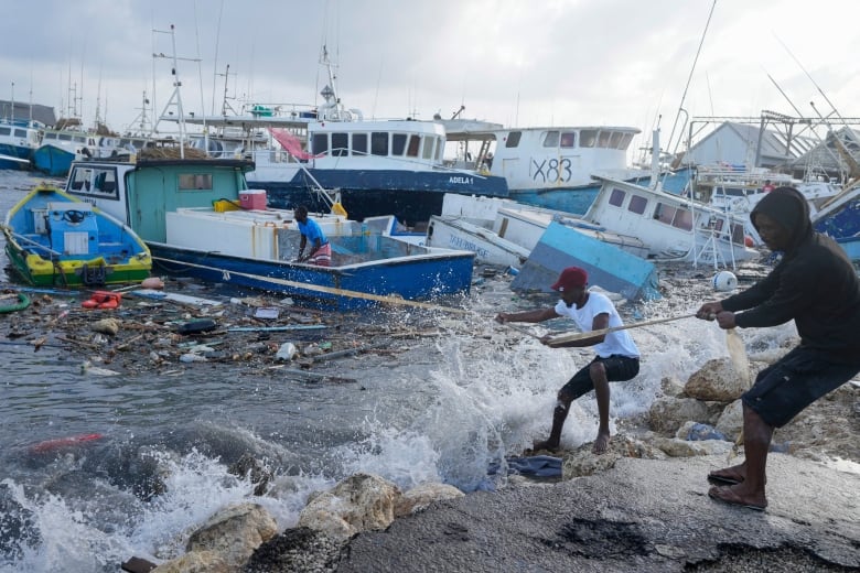 Fishermen pull a boat damaged by Hurricane Beryl back to the dock at the Bridgetown Fisheries in Barbados, Monday, July 1, 2024. 