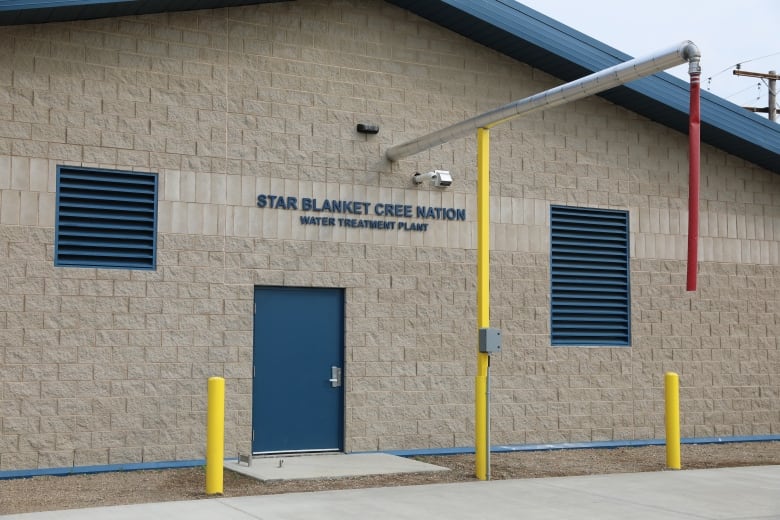 A brick building with a blue door and a blue roof. The phrase "Star Blanket Cree Nation Water Treatment Plant" is on the building. 