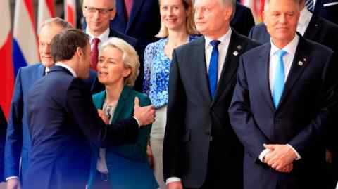 A man in a suit hugs a woman in a suit at a gathering of heads of state