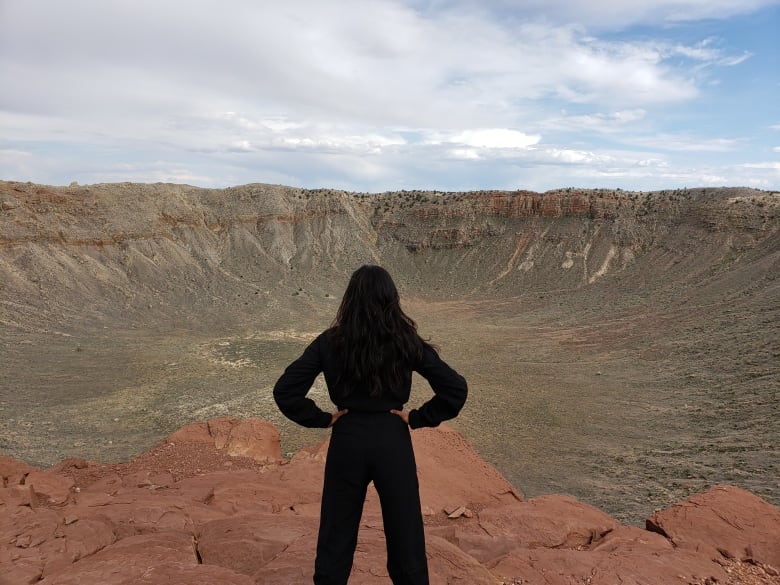 A woman stands in a at meteor crater.