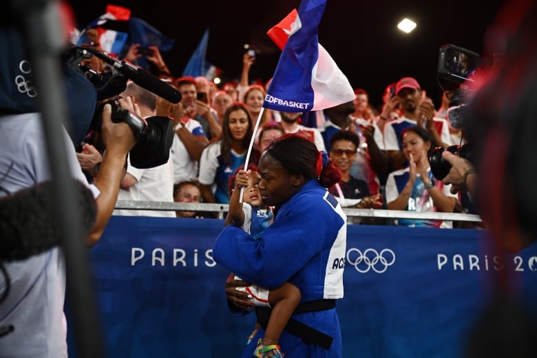 An athlete carries a  flag  and a baby