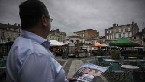 View over a man’s shoulder of the RN leaflet he is handing out in a market