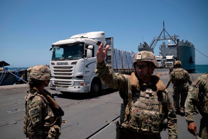 A US Army soldier gestures as trucks loaded with humanitarian aid arrive at the US-built floating pier Trident