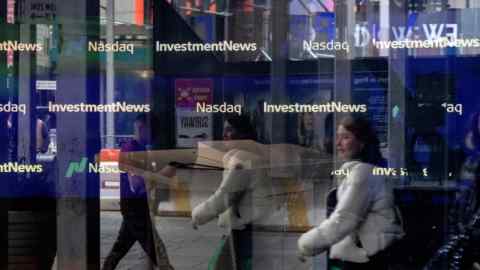 Pedestrians pass the Nasdaq Market site in New York