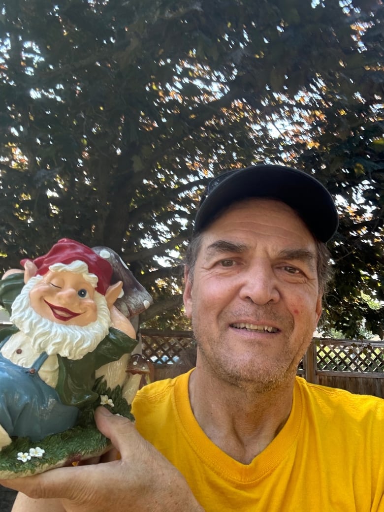 A man holds up a freshly painted garden gnome.