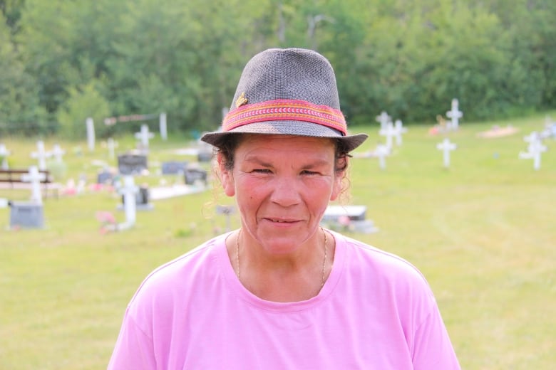 A woman stands with her hat on. 