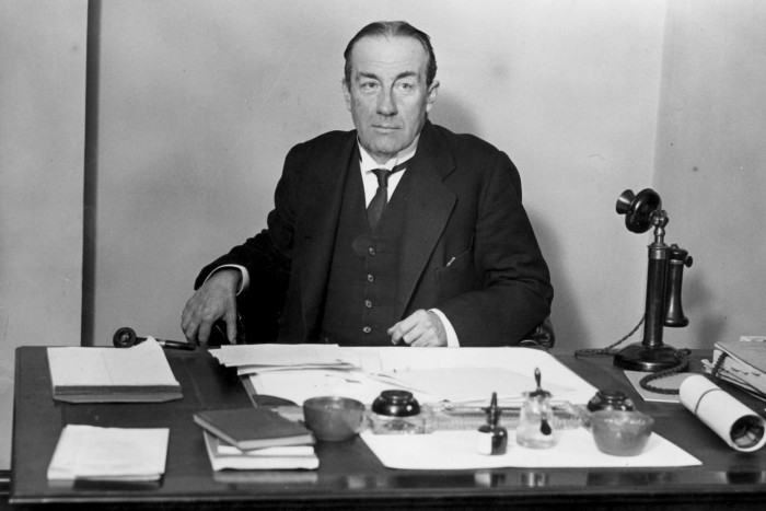 Stanley Baldwin sits at his desk