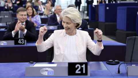 Ursula von der Leyen raises her firsts in celebration as European parliament members applaud in the background