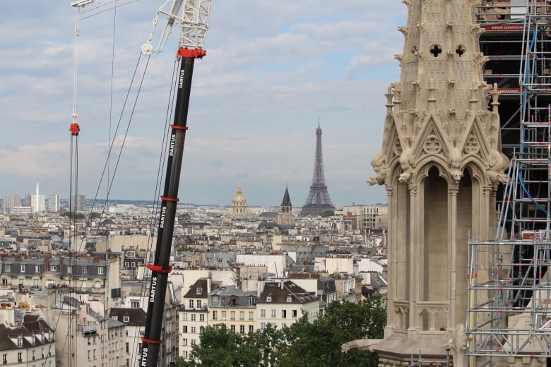 A skyline view of houses and a large tower. Part of a crane and a building under construction are seen on either side.