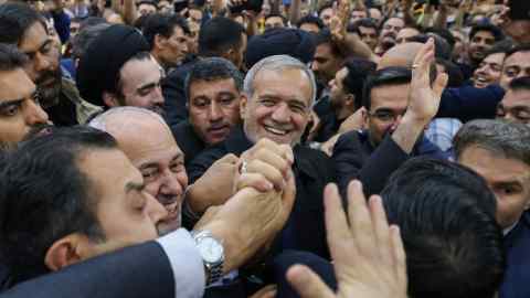 A smiling Masoud Pezeshkian surrounded by cheering suppporters