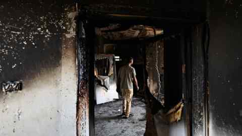 A Palestinian man stands in a house gutted by fire