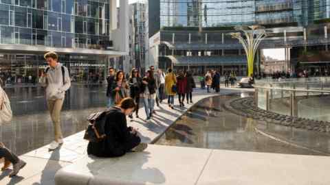 People walk past shiny office blocks in Milan