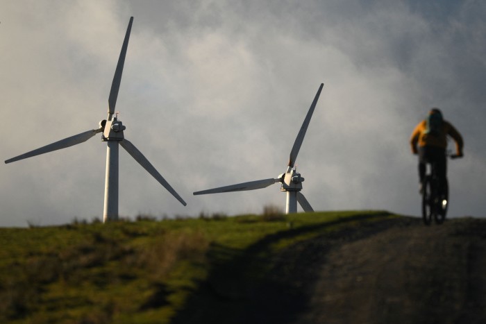 A cyclist rides past wind turbines in Wales